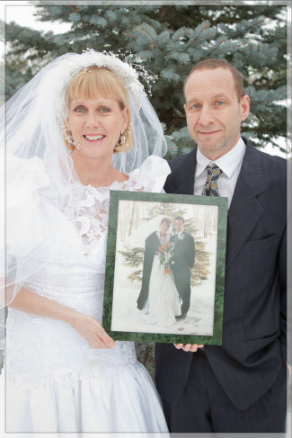 25th wedding Anniversary photo of couple in their wedding clothes holding a photo of their wedding day 
